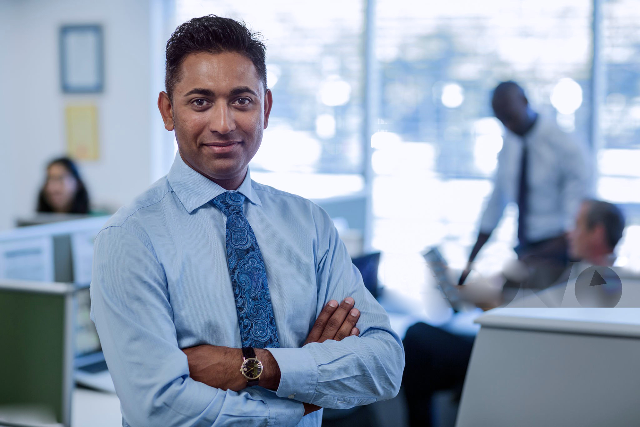 portrait of confident businessman standing arms crossed in office
