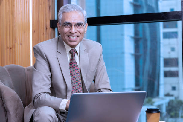indian businessman sitting on sofa and working on laptop at modern office